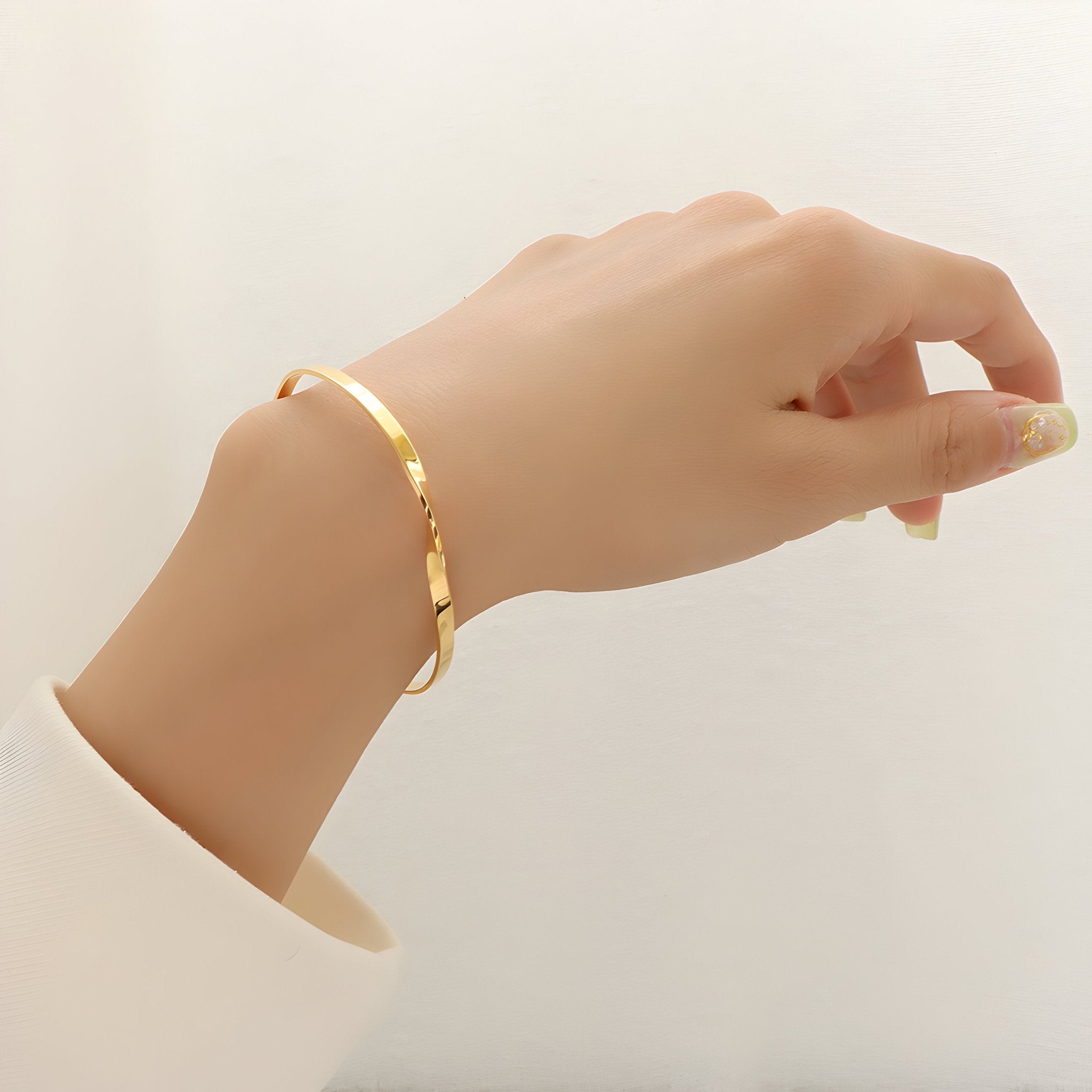 Bracelet fin en titane plaqué or 18 carats avec design distorsion moderne porté au poignet.