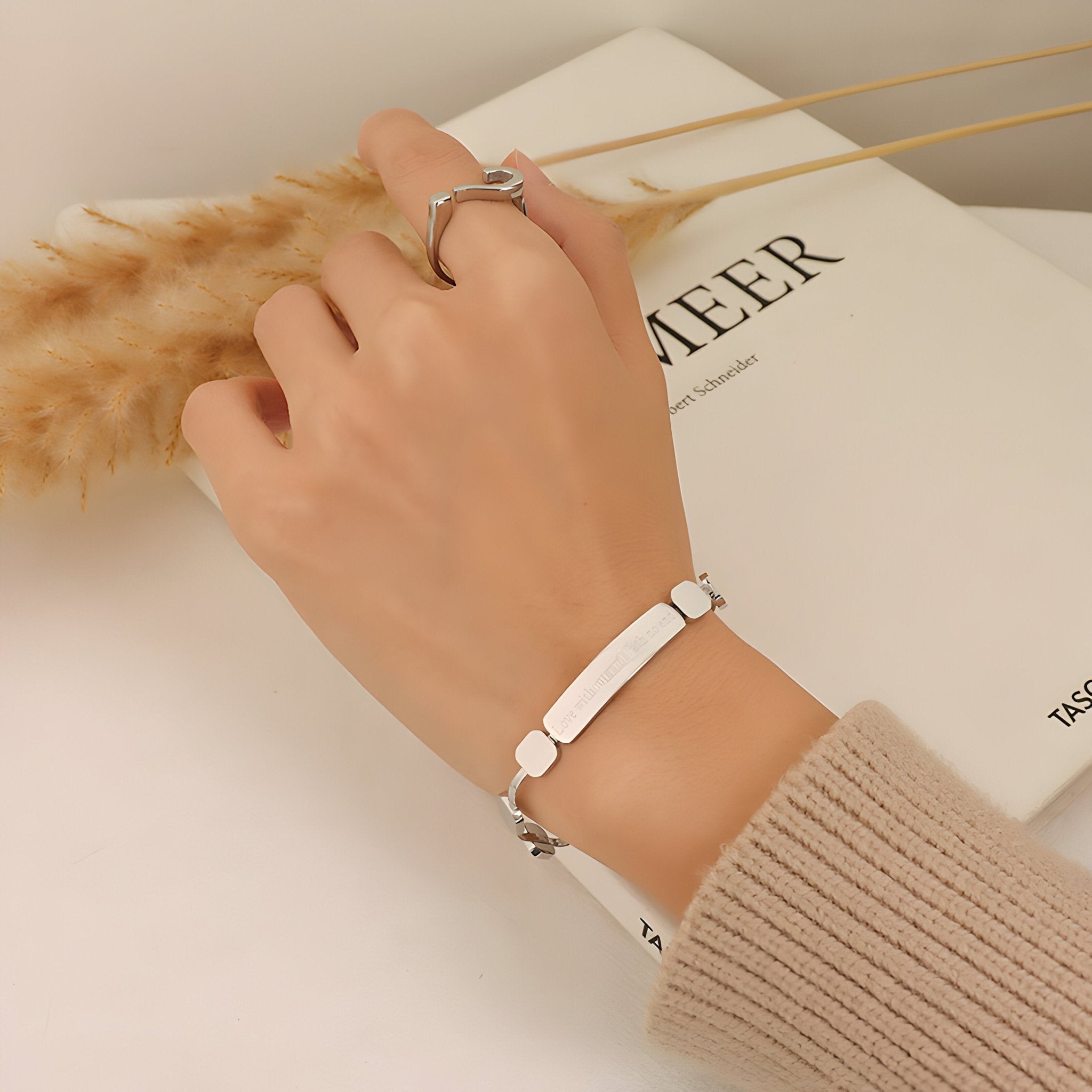 Bracelet fin en titane plaqué or 18 carats avec plaque gravée, porté au poignet, style moderne et épuré.