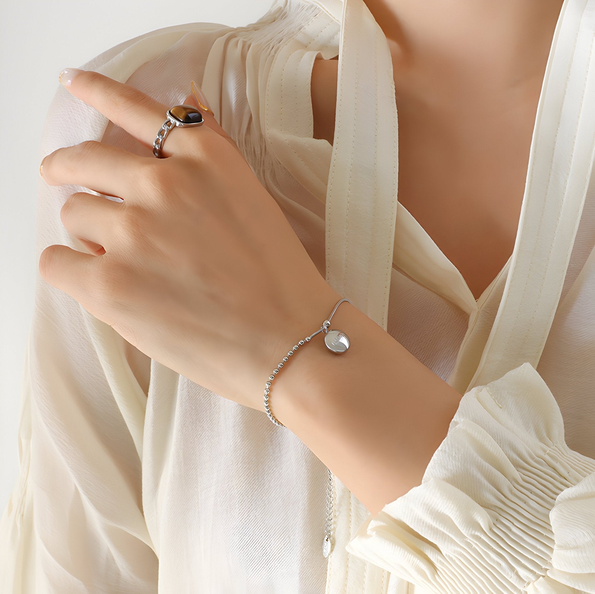 Bracelet fin en titane plaqué or 18 carats avec médaillon rond gravé « Lucky » porté au poignet féminin.