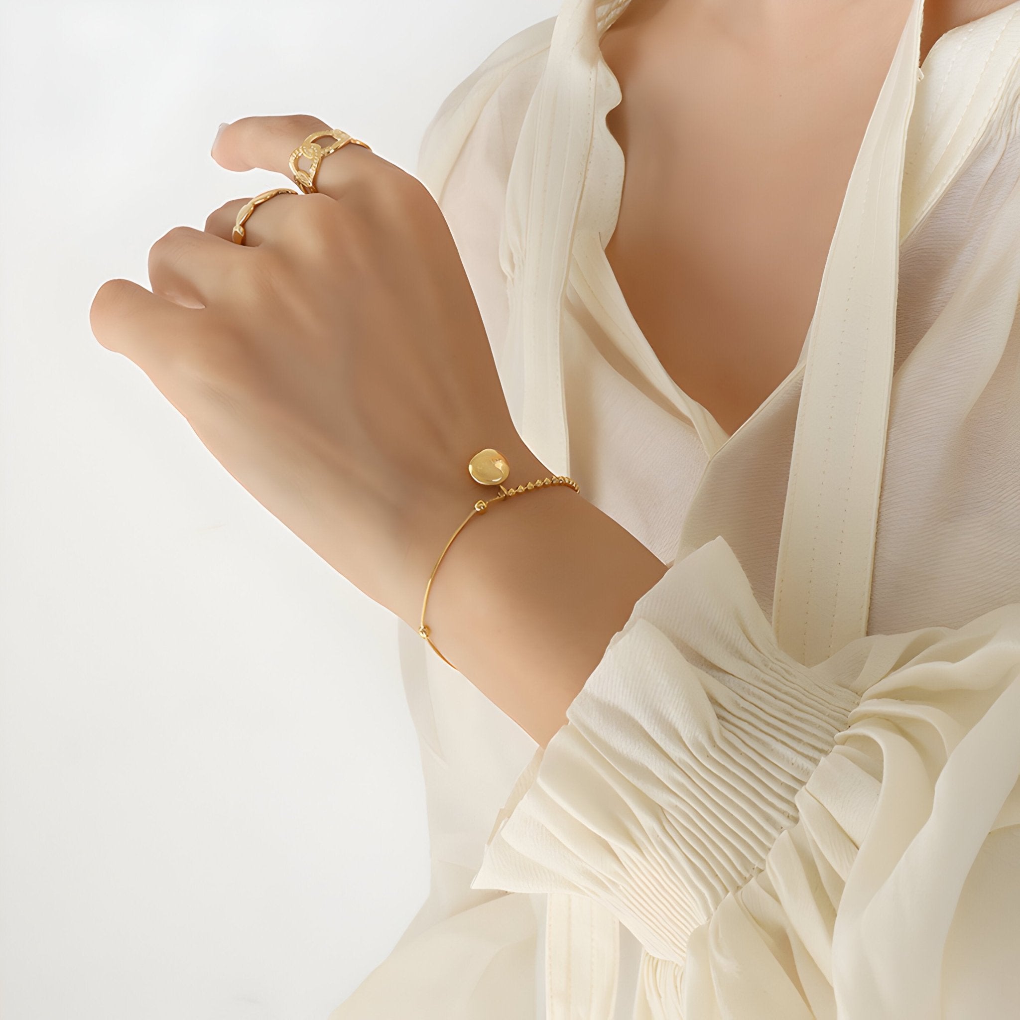 Bracelet fin en titane plaqué or 18 carats avec médaillon rond gravé "Lucky" porté au poignet.