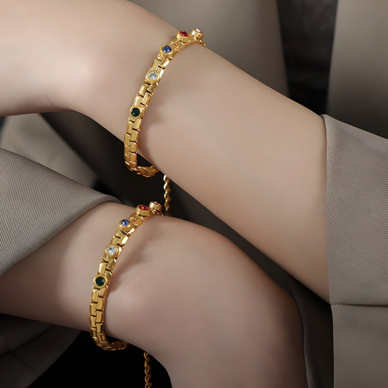 Bracelet en titane plaqué or avec incrustations de pierres de zircon multicolores, modèle Daisy, porté au poignet.