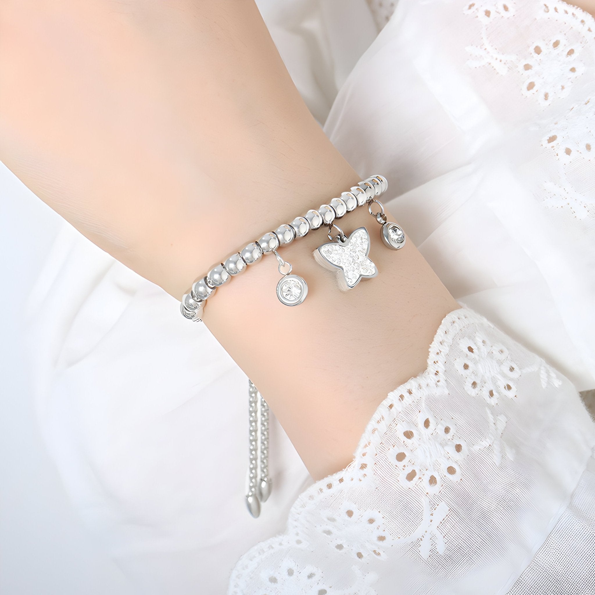 Bracelet en titane plaqué argent avec médaillon papillon et breloque ronde scintillante.
