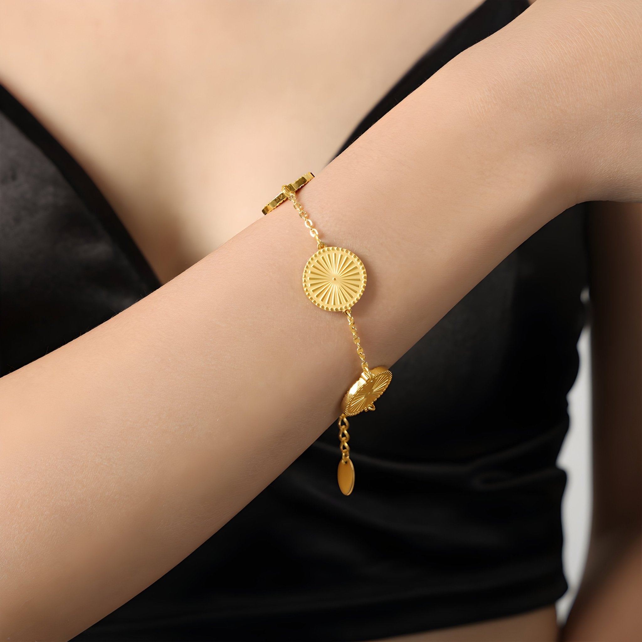 Bracelet en titane plaqué or avec médaillons rayonnants ronds sur poignet féminin, style élégant.