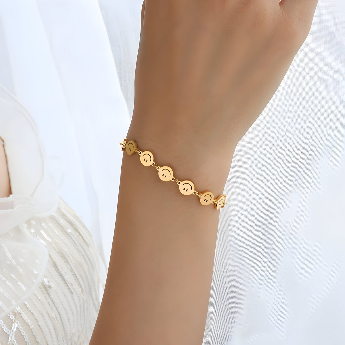 Bracelet en titane plaqué or avec motifs smileys ronds, chaîne fine élégante sur poignet féminin.