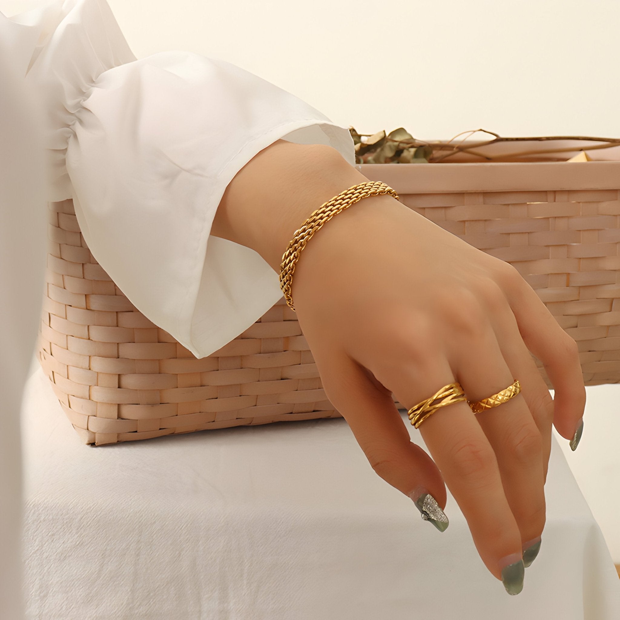 Bracelet en titane plaqué or style maillon fin porté au poignet féminin avec bague assortie dorée.