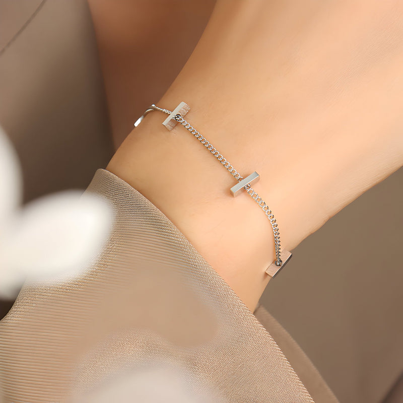 Bracelet fin en titane plaqué or avec chaînes délicates et croix minimalistes.