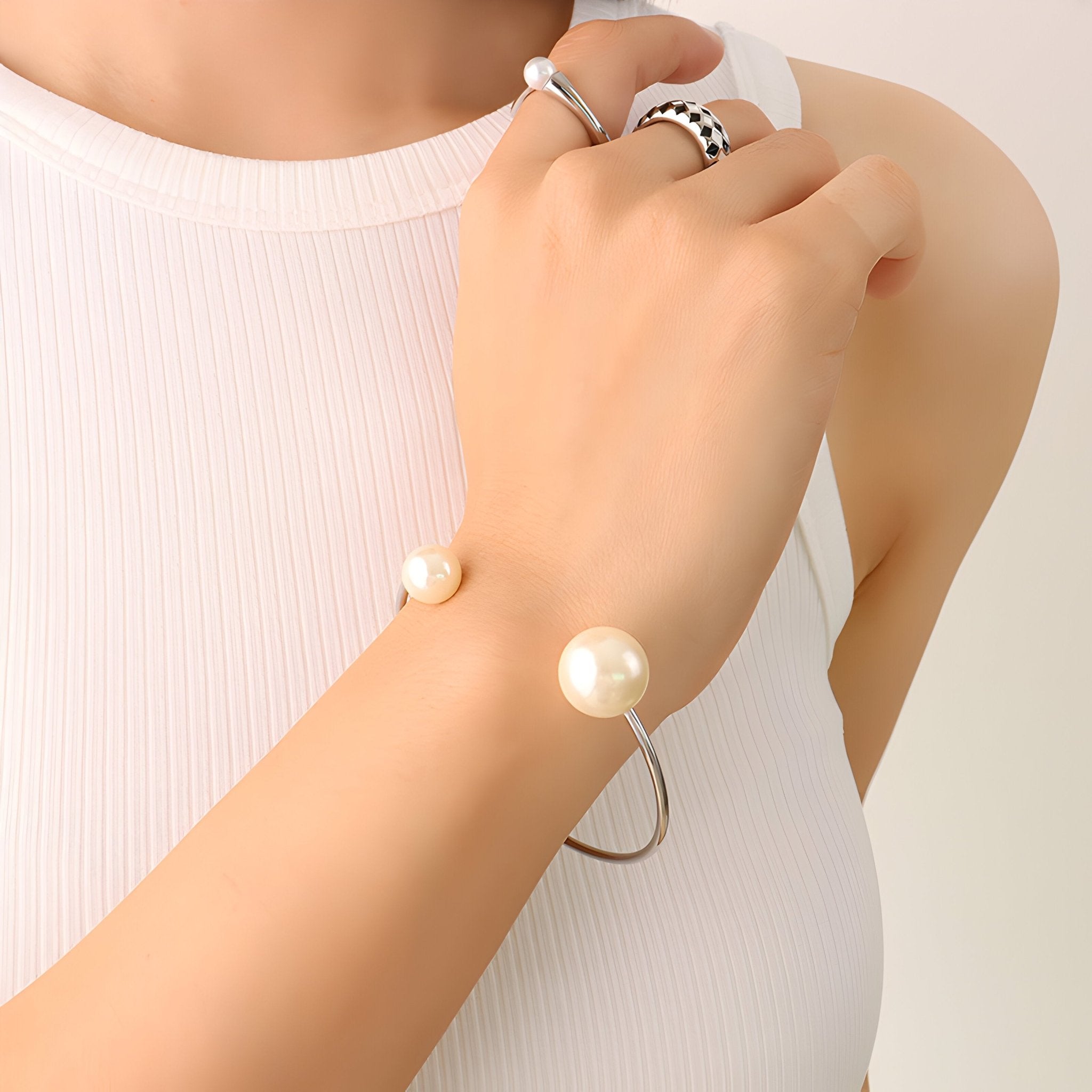Bracelet jonc en titane plaqué or 18 carats avec perles d’imitation aux extrémités porté au poignet.