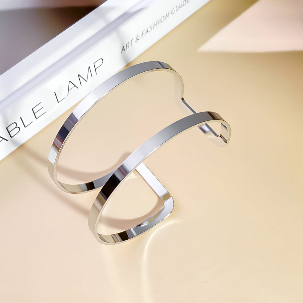 Bracelet manchette double rang en métal argenté lisse et brillant, style minimaliste élégant.