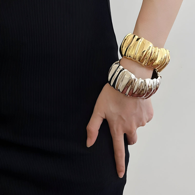 Bracelets manchette ondulés en métal or et argent au fini texturé, style moderne et élégant.