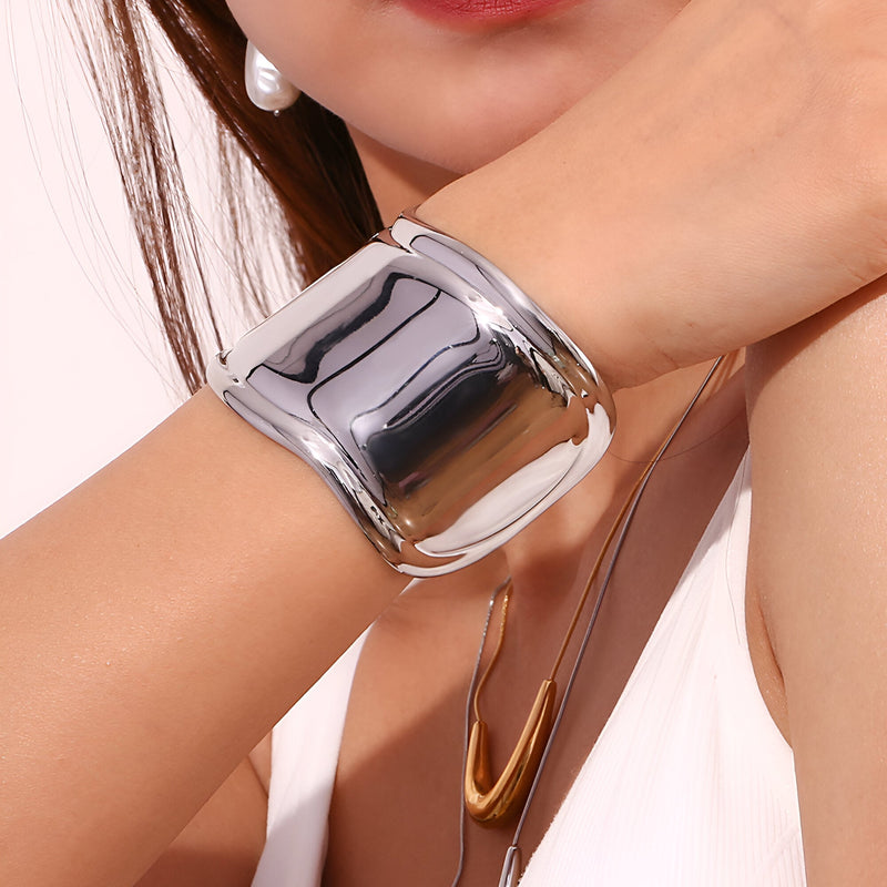 Bracelet manchette en acier inoxydable argenté, finition miroir brillante, design large et incurvé.