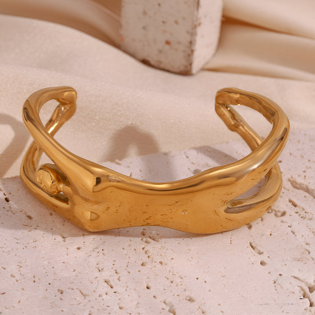 Bracelet manchette doré en métal avec design sculpté en forme de buste féminin stylisé.
