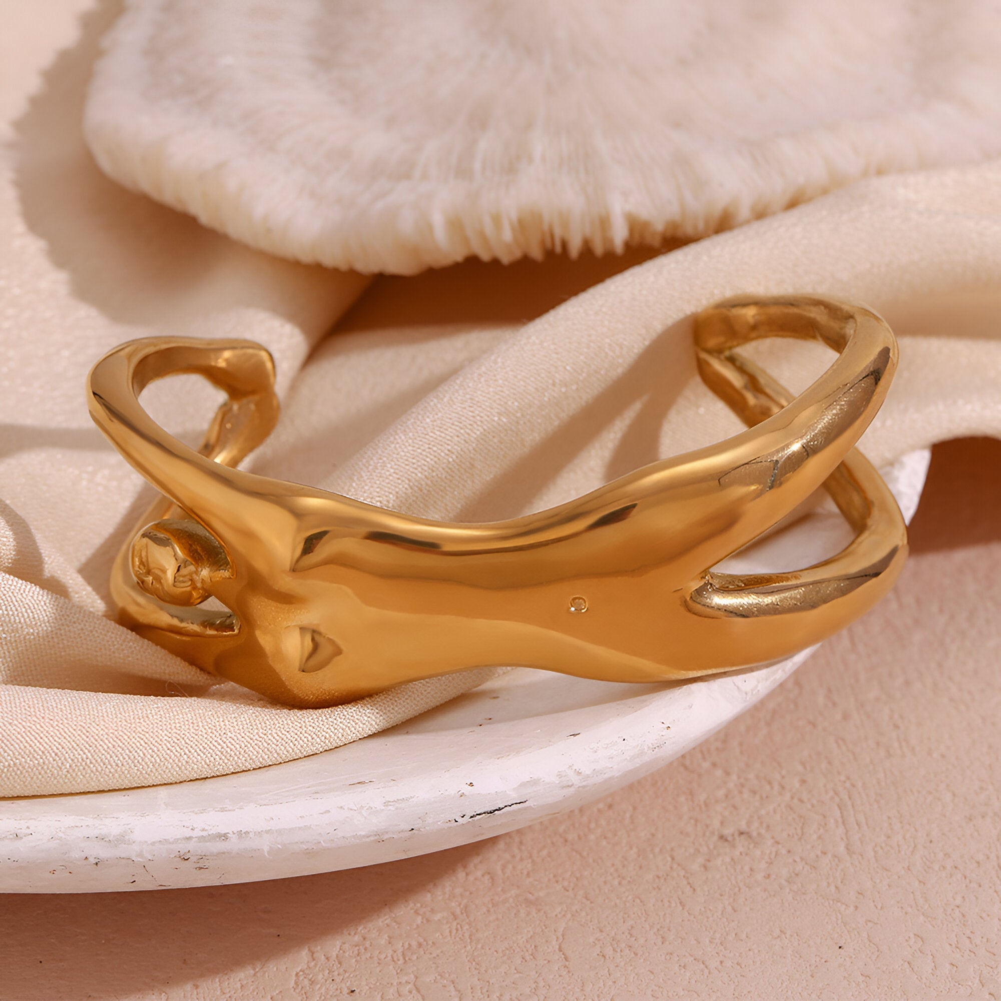 Bracelet manchette or en métal brillant en forme de buste féminin stylisé, finition lisse et courbes élégantes.