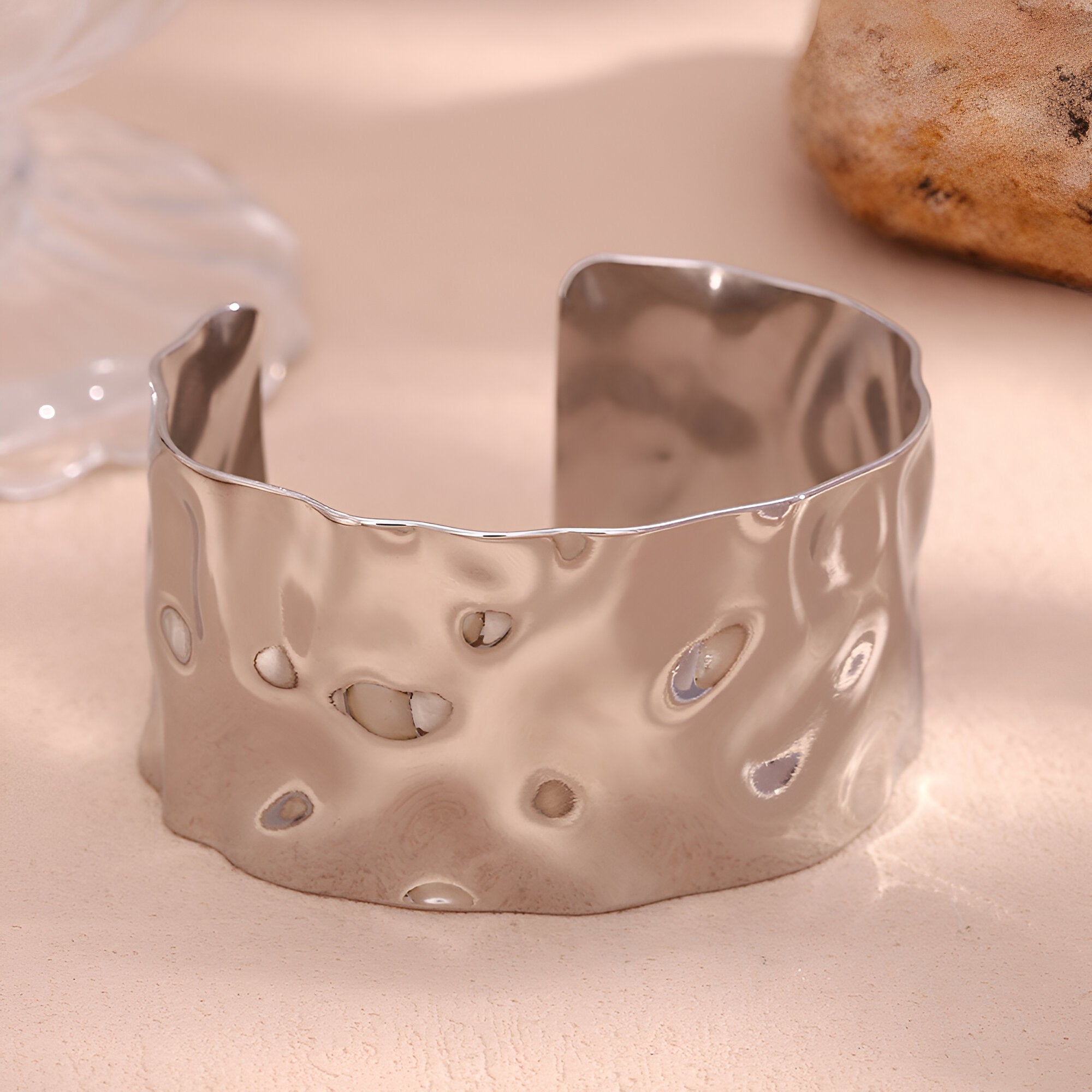 Bracelet manchette en acier inoxydable argenté avec surface ondulée et texture martelée.