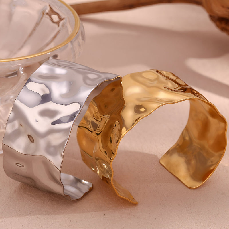 Bracelet manchette ondulé en acier inoxydable, finition or brillant et argent poli, design texturé fluide.