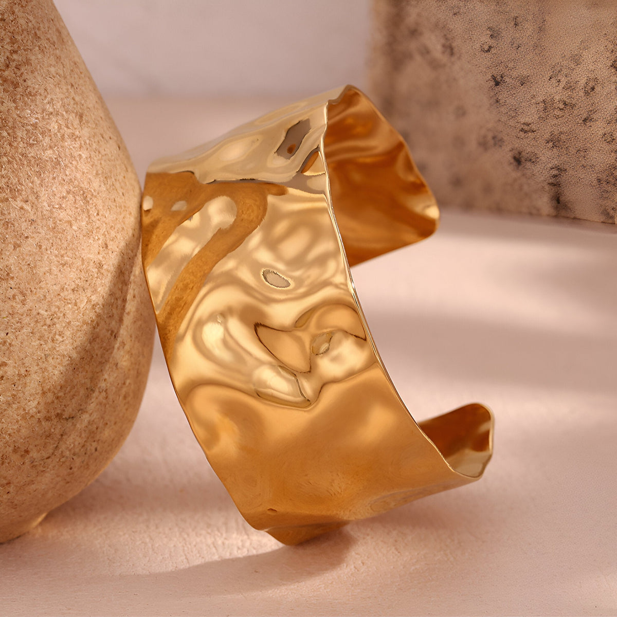 Bracelet manchette ondulé en acier inoxydable doré brillant au design fluide et texturé.
