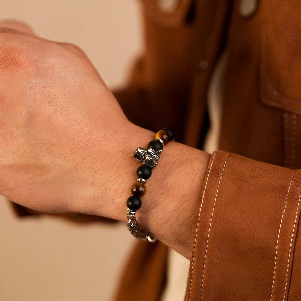 Bracelet homme perles marron oeil de tigre et tête de loup argentée sur poignet.