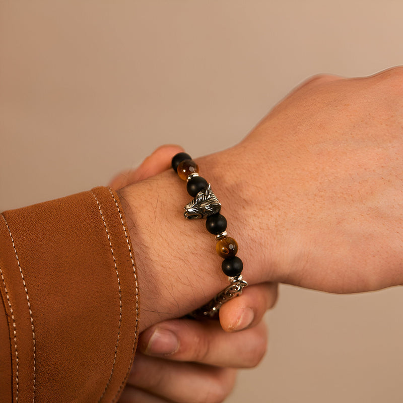 Bracelet homme avec perles en œil de tigre marron et tête de loup argentée détaillée.