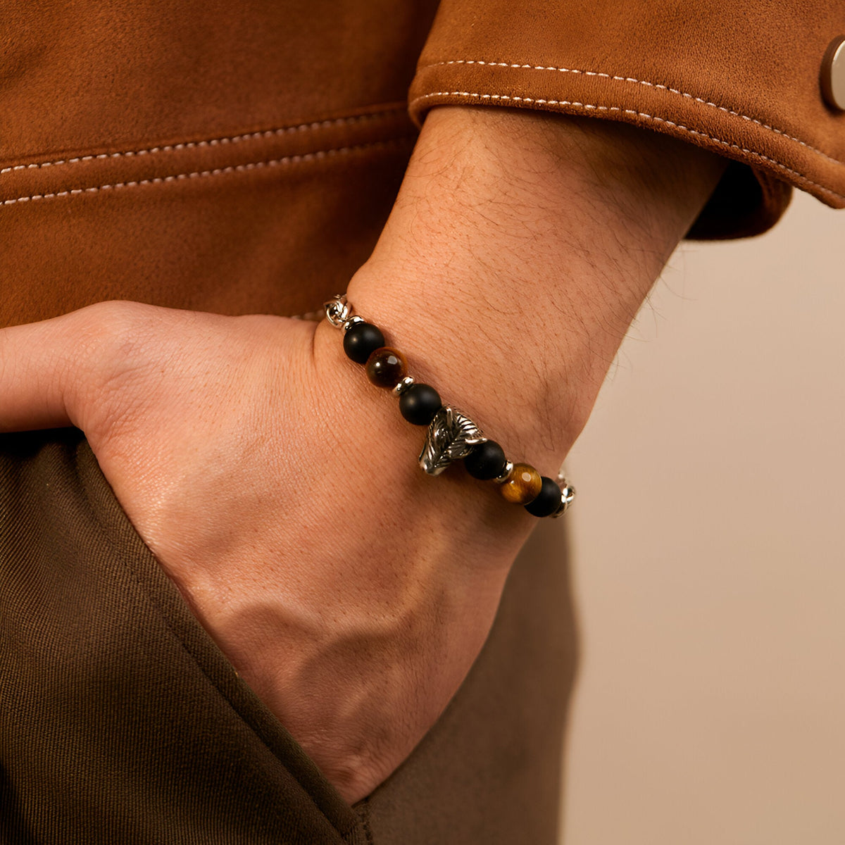 Bracelet pour homme avec perles noires et œil de tigre, tête de loup en métal gris vieilli.