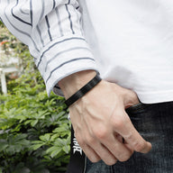 Bracelet jonc homme en acier inoxydable noir, design épuré et moderne, porté au poignet.