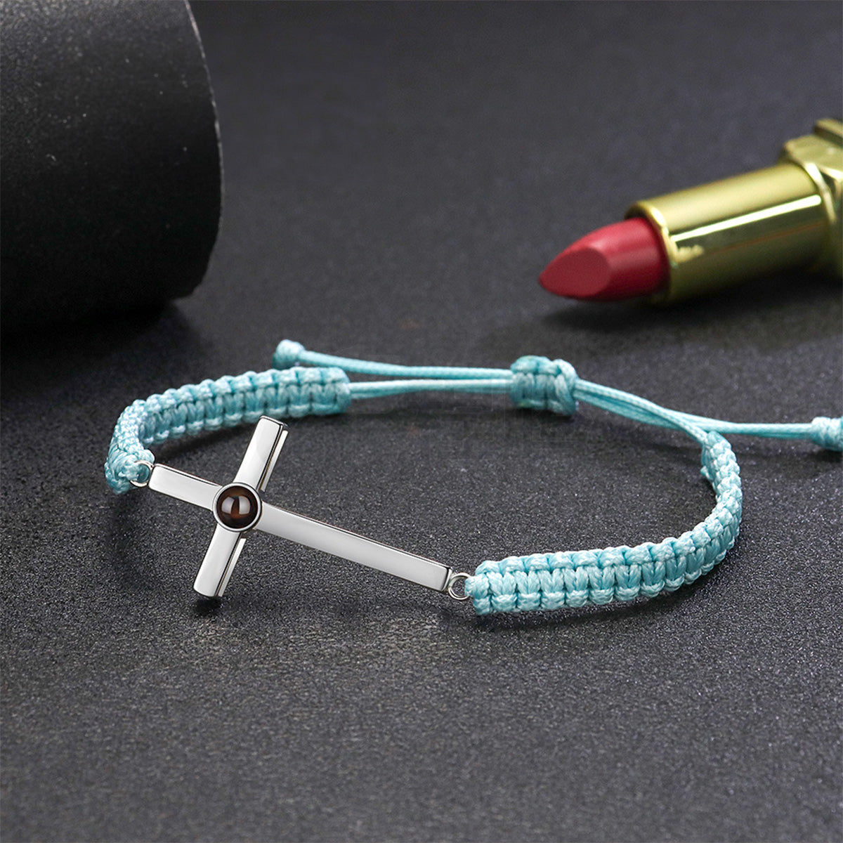 Bracelet à cordon bleu clair avec croix en argent et petit médaillon gravé intégré.