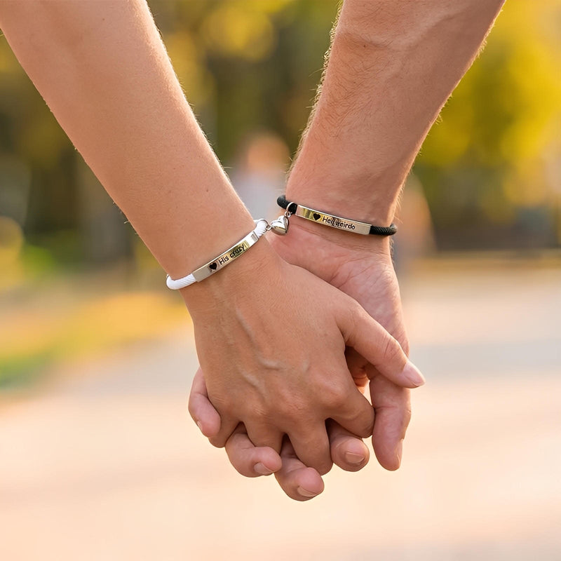 Bracelets couple en acier inoxydable argenté avec corde noire et cœur aimanté gravé, porté aux poignets entrelacés.