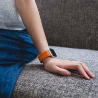 Bracelet Apple Watch en nylon orange avec boucle technique, modèle Arès, porté au poignet féminin.