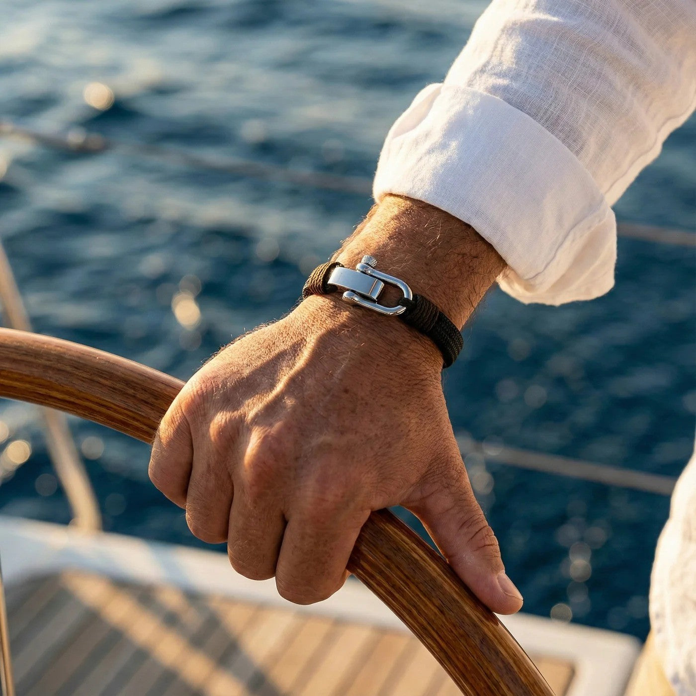 Bracelet homme en coton noir tressé avec fermoir manille en acier inoxydable gris, style marin, porté au poignet.