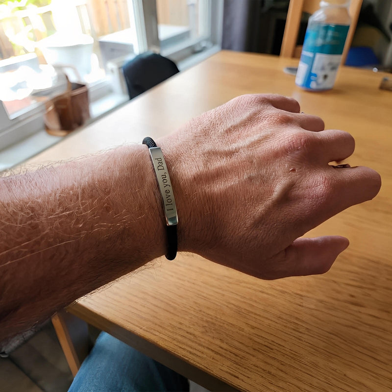 Bracelet fin en cordon noir avec barre en acier inoxydable gravée, fermoir coulissant ajustable.