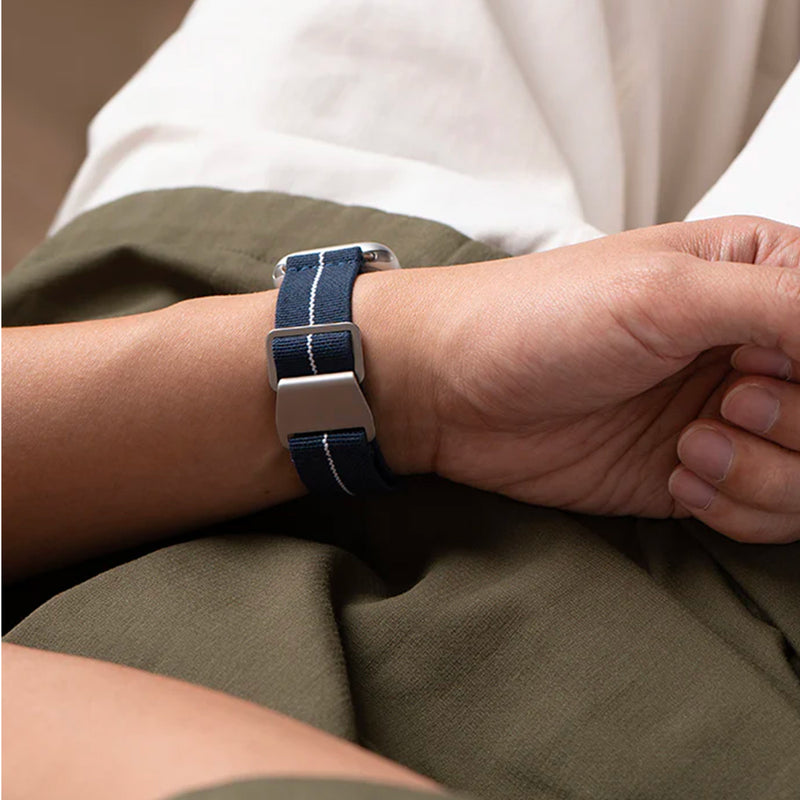 Bracelet Apple Watch en nylon bleu marine avec boucle technique argentée et couture blanche visible.