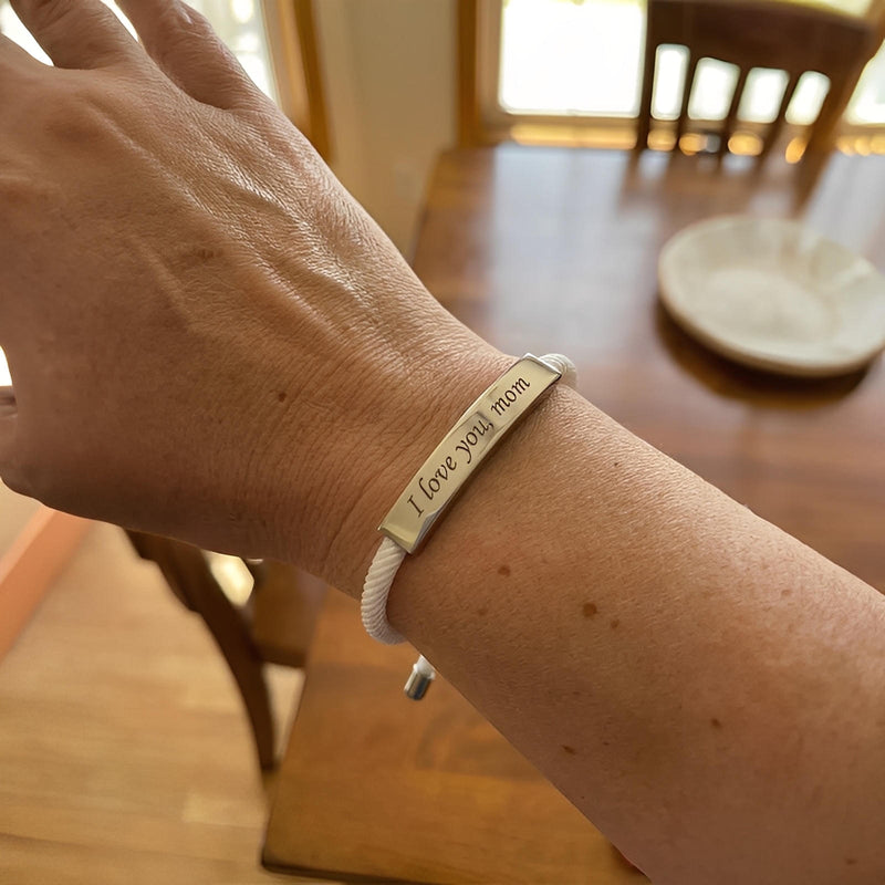 Bracelet cordon nylon blanc avec barre acier inoxydable gravée « I love you » et fermoir coulissant.