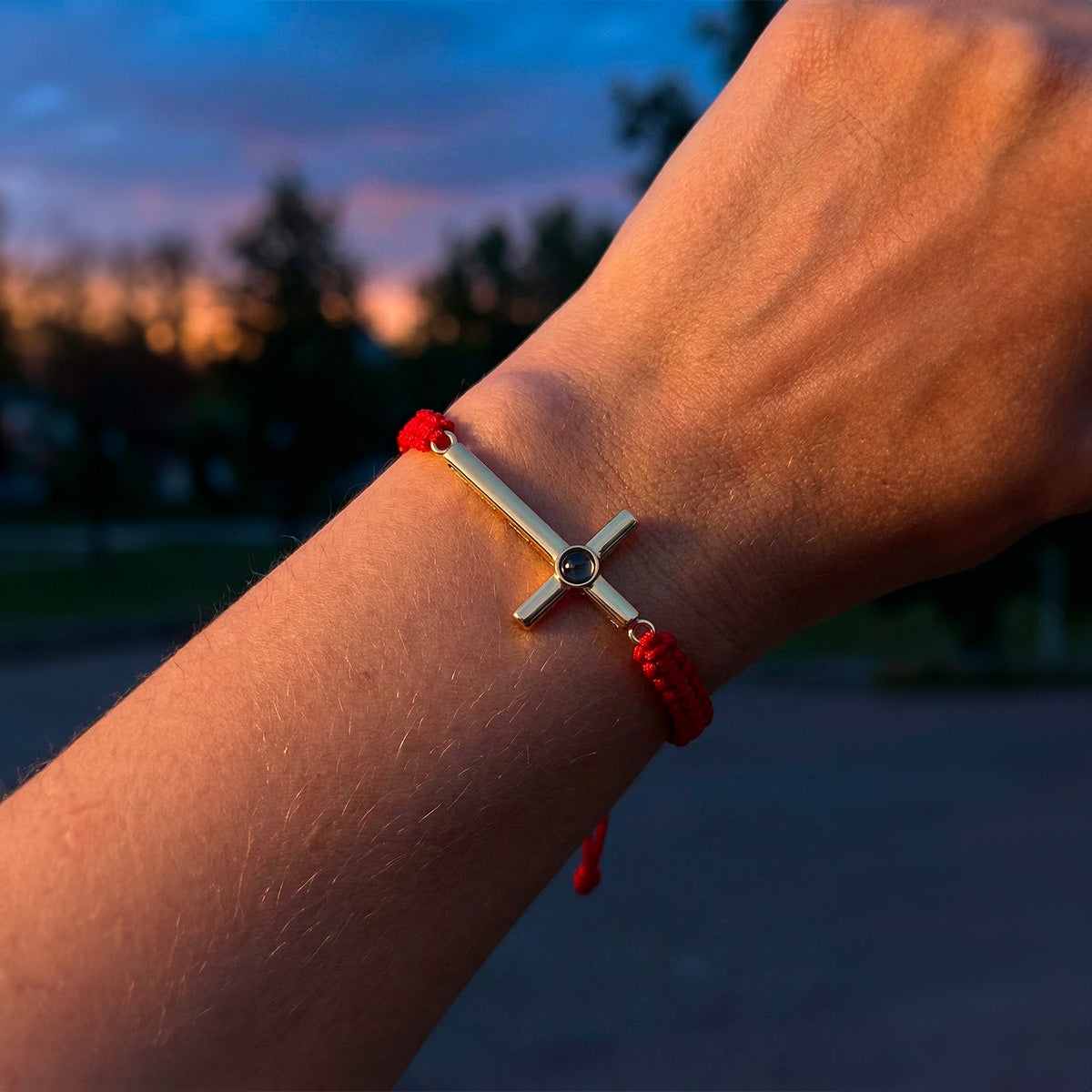 Bracelet rouge à cordon coulissant avec pendentif croix en argent et gravure centrale.