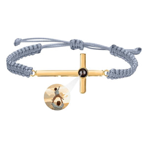 Bracelet à corde grise coulissante avec pendentif croix en argent doré et centre noir gravé.