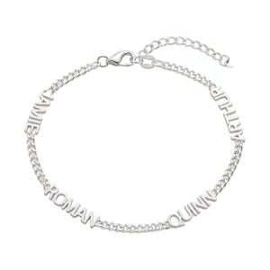 Bracelet en acier inoxydable argenté avec maille cubaine fine et quatre prénoms taillés autour du poignet.