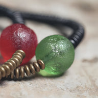 Bracelet en ébène noir avec perles en verre rouge et vert texturé, détails en métal cuivreux.