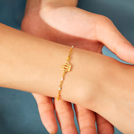Bracelet fin doré avec pendentif couronne minimaliste sur poignet féminin.