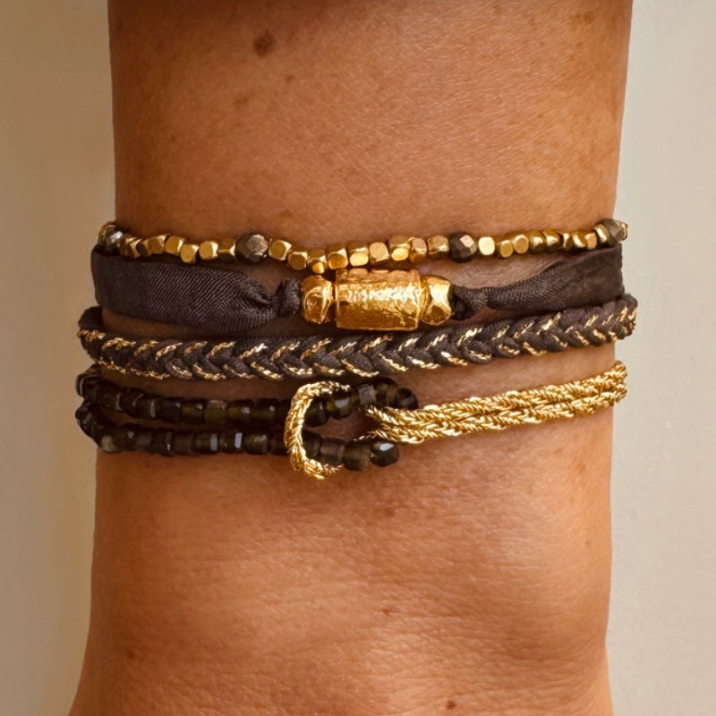 Bracelet double rang avec perles dorées, corde torsadée marron et or, fermoir mousqueton lumineux, nœud décoratif raffiné.