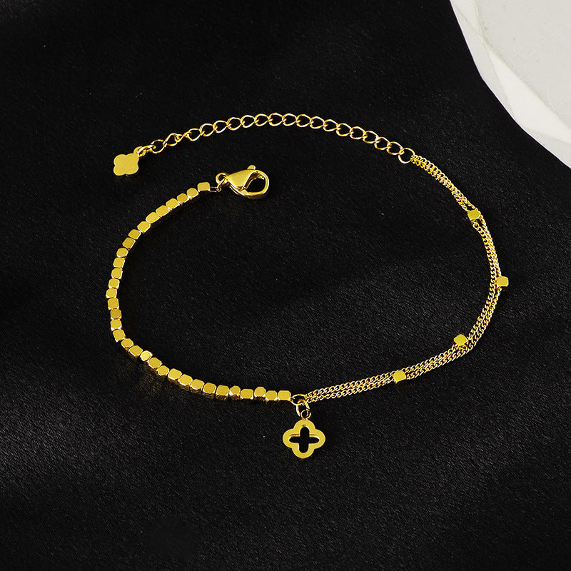 Bracelet doré fin en titane avec double chaîne et pendentif trèfle porte-bonheur délicat.