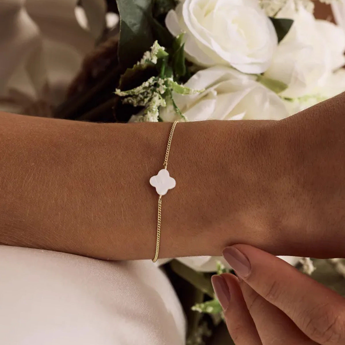 Bracelet doré fin avec pendentif trèfle blanc en pierre naturelle, ajustable et délicat.