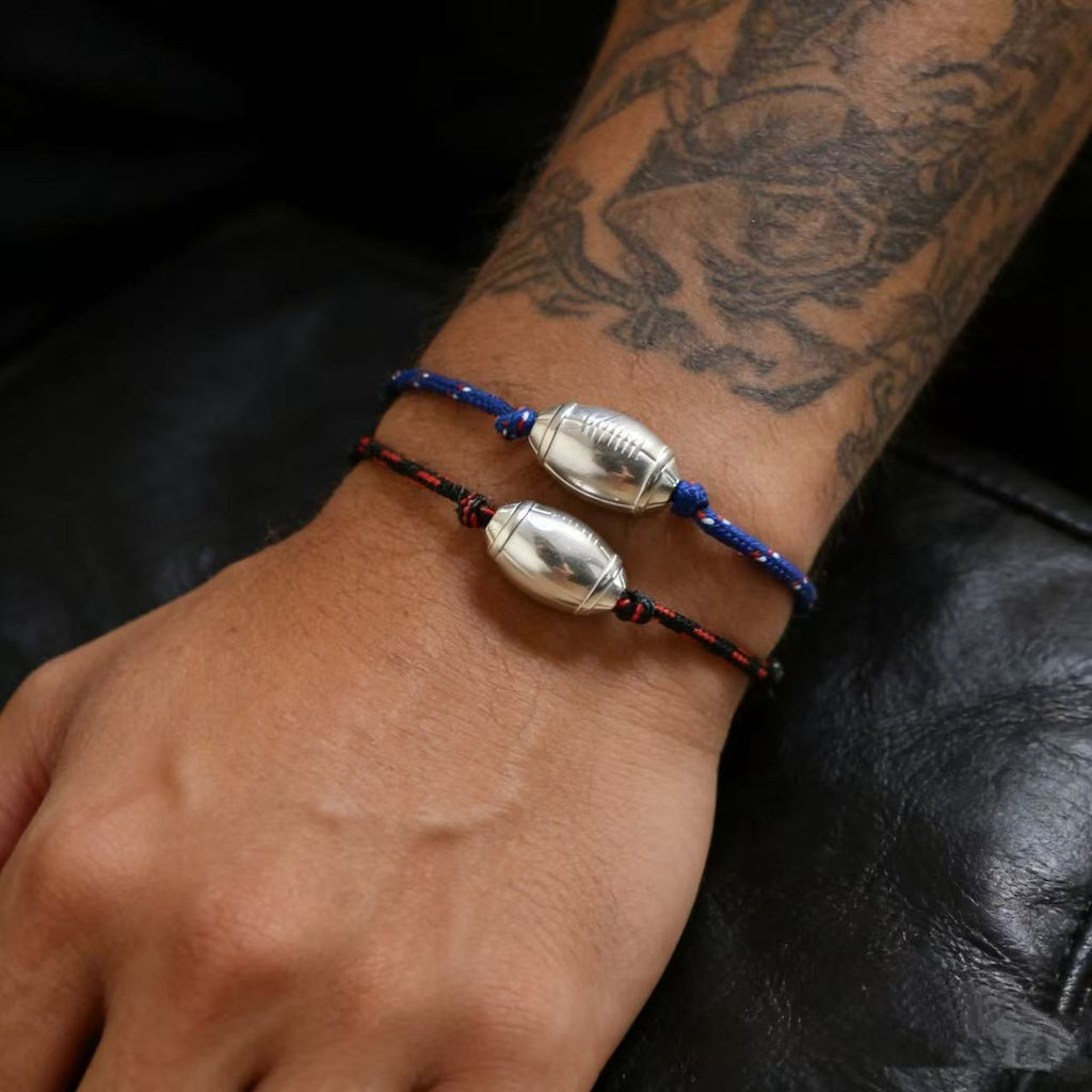 Bracelet cordon bleu avec perle argentée en forme de ballon de rugby, style sportif masculin.
