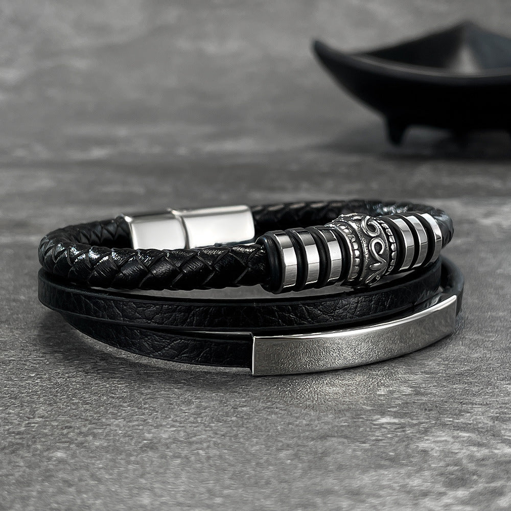 Bracelet homme double tour noir en simili cuir tressé et lisse avec fermoir aimanté métallique argenté et détails gravés.