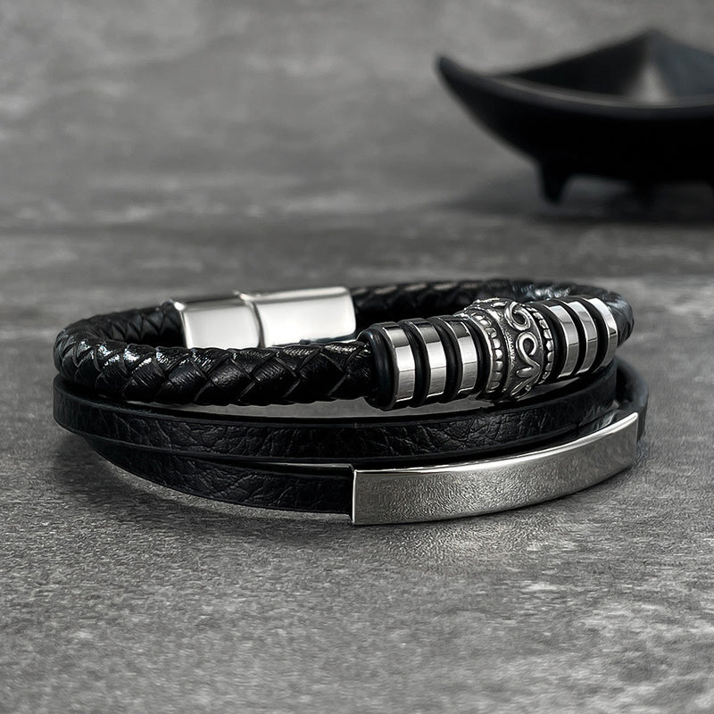 Bracelet homme double tour noir en simili cuir tressé et lisse avec fermoir aimanté métallique argenté et détails gravés.