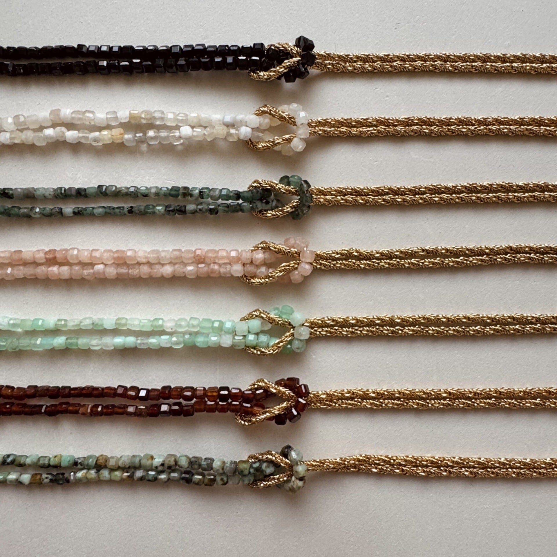 Bracelet double rang avec perles japonaises multicolores, corde dorée torsadée, fermoir mousqueton et nœud décoratif.