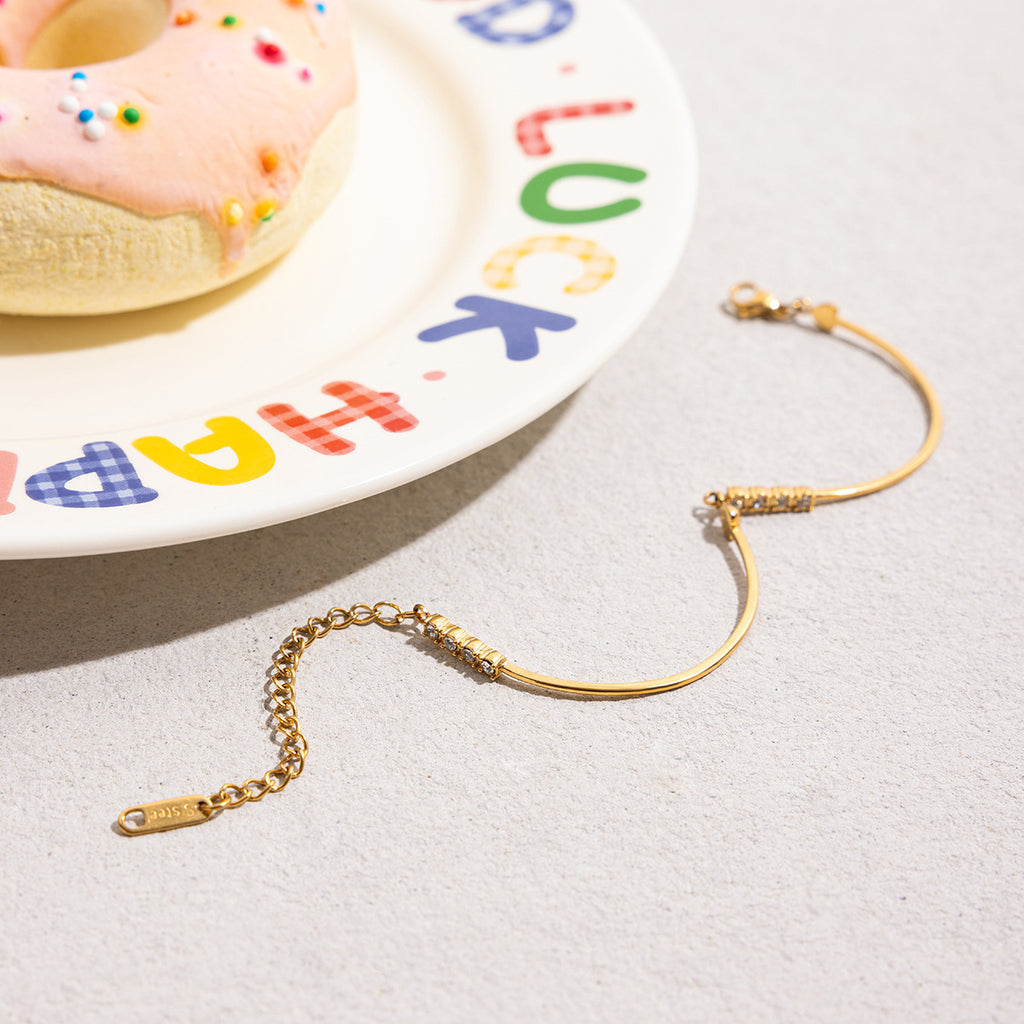 Bracelet jonc doré fin avec pendentif cœur orné de petits zircons scintillants et chaîne ajustable avec fermoir mousqueton.