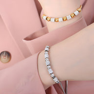 Bracelet en titane plaqué or orné de perles dorées et pierres de cristal scintillantes sur poignet féminin.