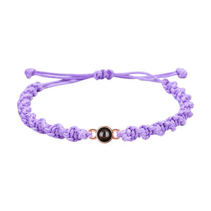 Bracelet tressé en nylon violet avec fermoir coulissant et médaillon circulaire noir central.