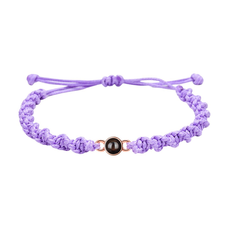 Bracelet tressé en nylon violet avec fermoir coulissant et médaillon circulaire noir central.