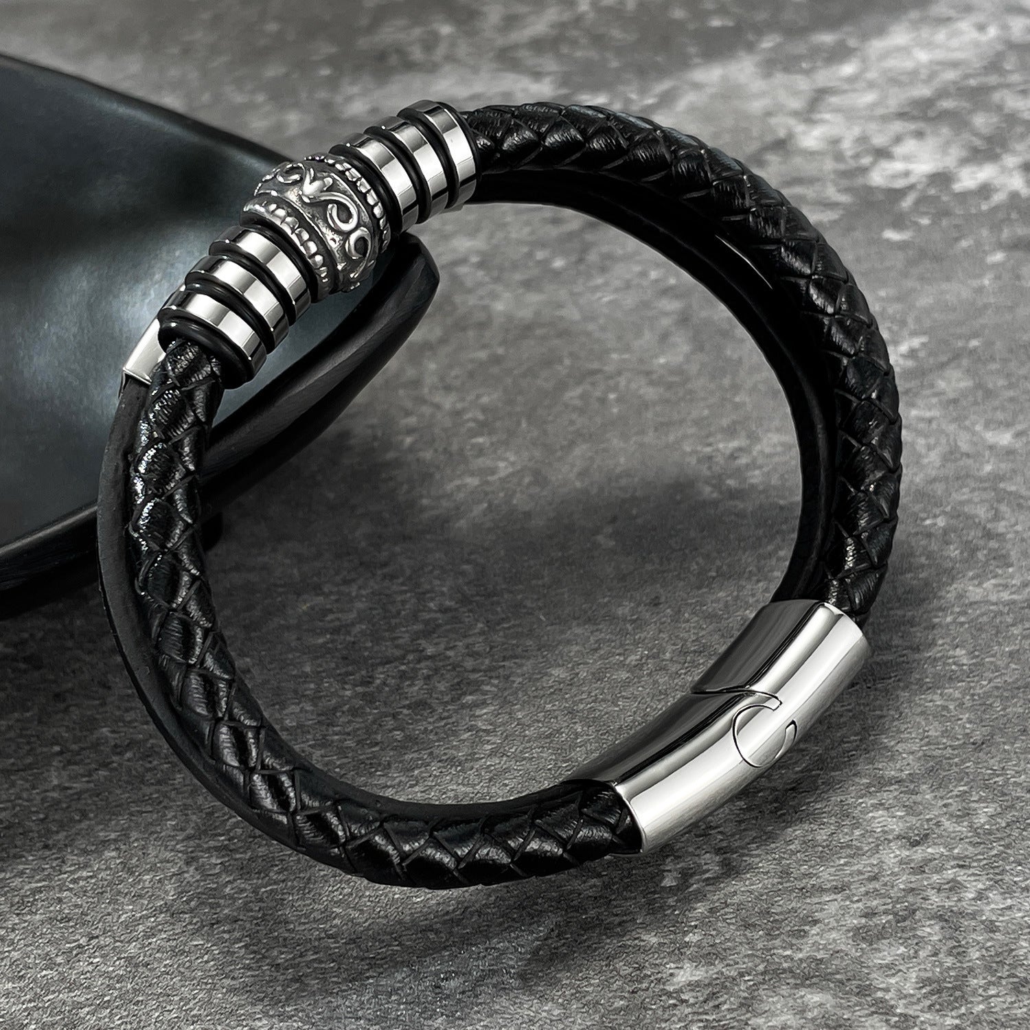 Bracelet homme en simili cuir noir tressé avec plaque gravée métallique et fermoir aimanté argenté.