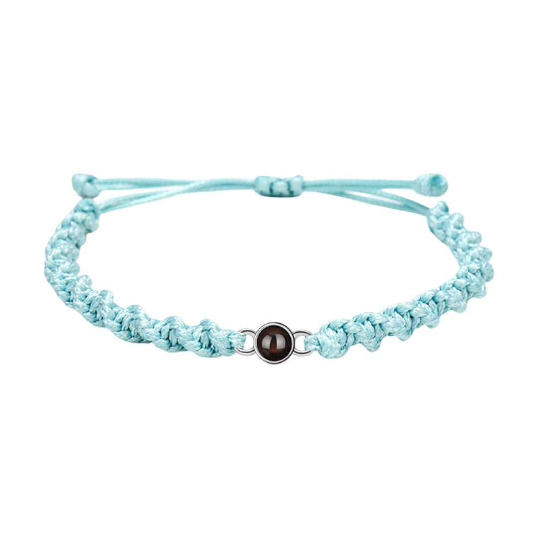 Bracelet tressé en nylon bleu clair avec fermoir coulissant métallique rond et photo projetée.