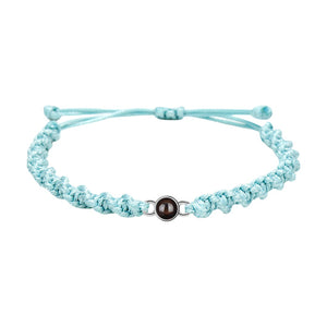 Bracelet tressé en nylon bleu clair avec fermoir coulissant métallique rond et photo projetée.