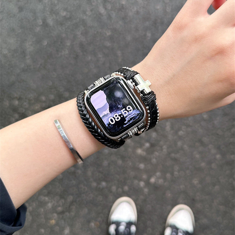 Bracelet Apple Watch tressé en simili cuir vegan noir multi-tours avec croix métallique argentée, look moderne et audacieux.